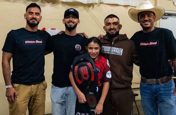 Bell receiving her championship belt surrounded by WBJJ coaches