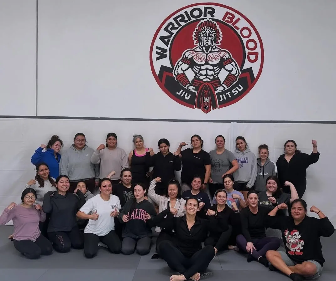 WBJJ women's class flexing together under the Warrior Blood logo